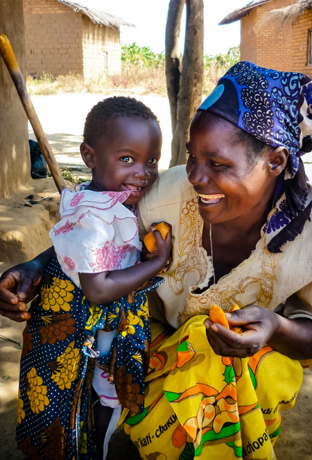 In Africa, a woman smiles holding her child 