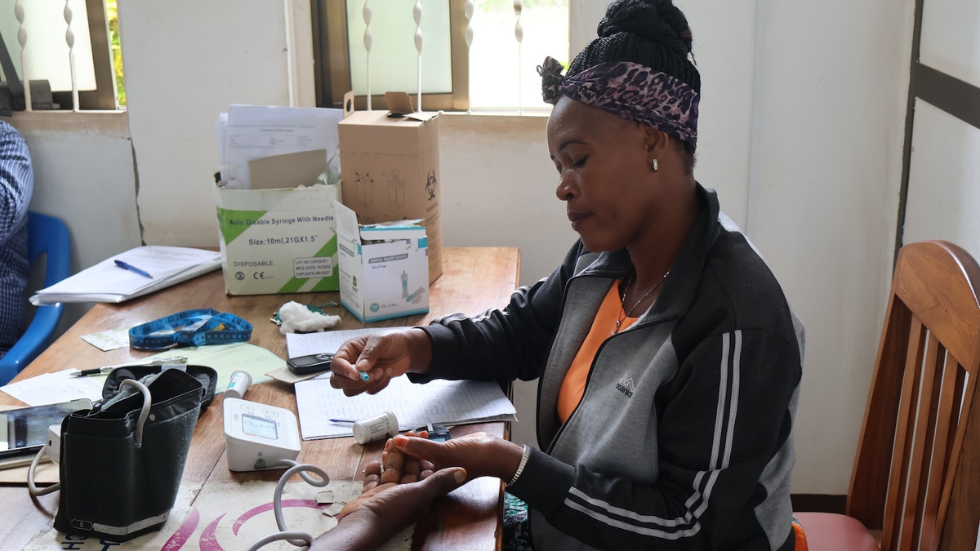 In Tanzania, a woman conducts blood drop testing as part of diabetes services