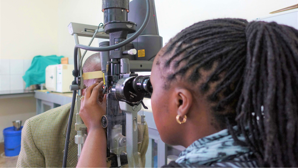 a doctor looks down a slit lamp machine at a patient's eyes 