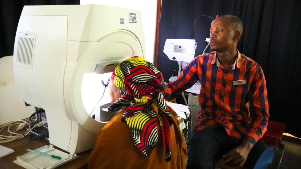 a health worker assists and older woman at a visual field analyser