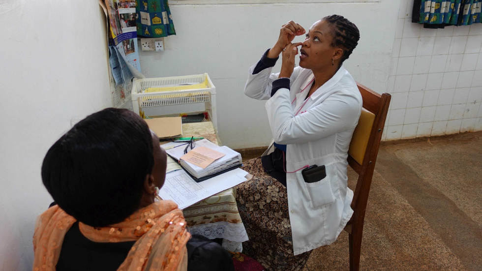a health worker demonstrates how to administer eye drops