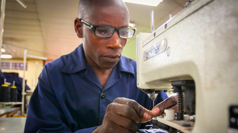 In Bangladesh, a worker at a garment factory smiles at the camera wearing glasses