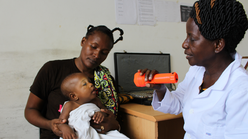 a health worker uses a torch to see a child's eyes