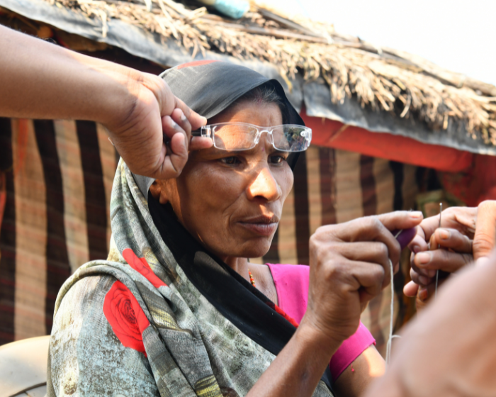 In India, a woman has glasses fitted while she sews