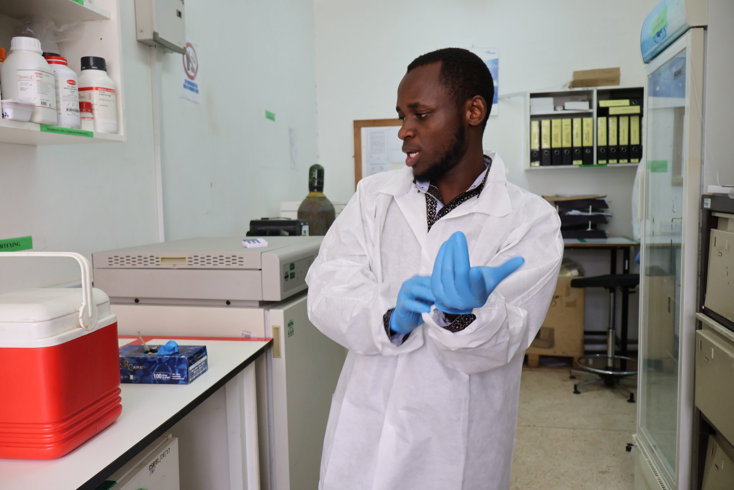 In Tanzania, a health worker puts on gloves in a lab 