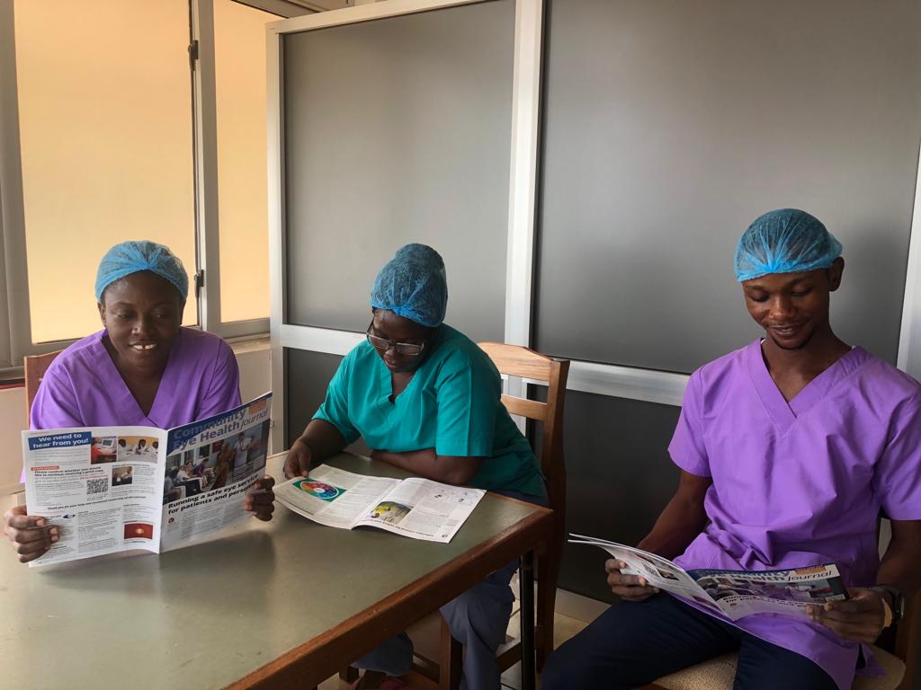 a group of health workers in brightly coloured scrubs read the community eye health journal