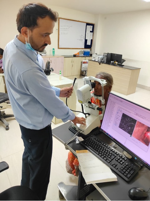 In Nepal a doctor stands at a microscopy camera while a woman is screened