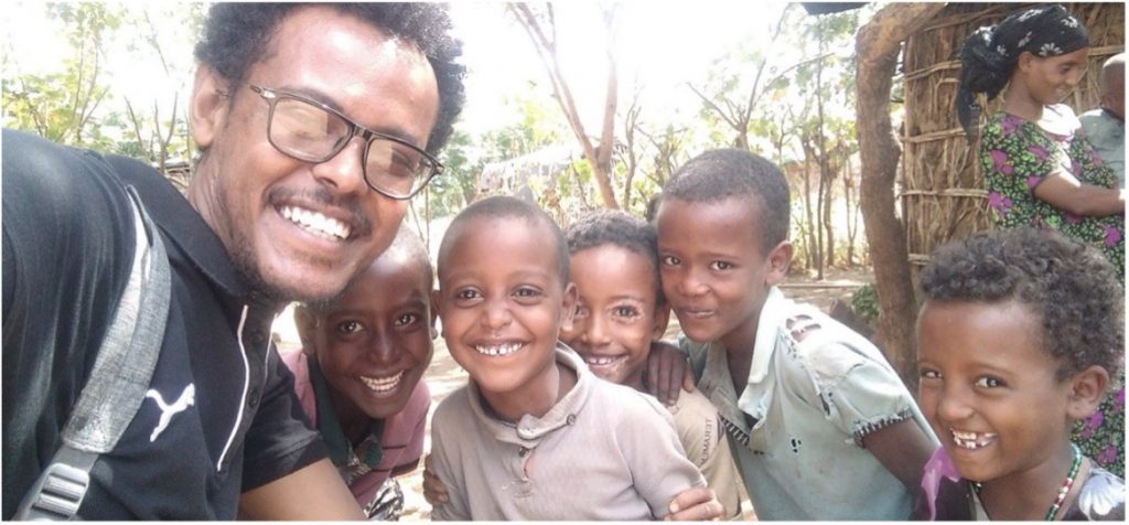 a photo of a man smiling with some children