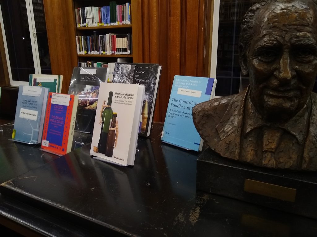 Photograph of Dry January book display consisting of eight books, with bust of Sir Richard Doll on the right.