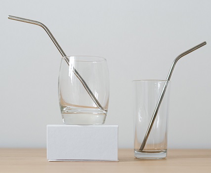 Different glasses with straws on table on white background