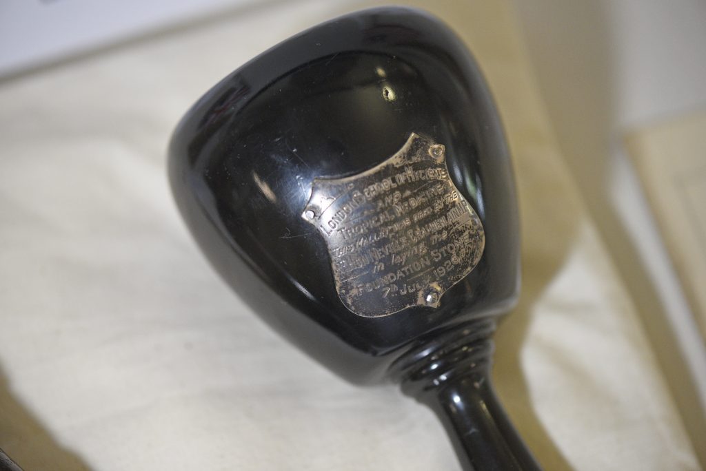 Close up of black mallet showing a faded silver plaque reading 'London School of Hygiene and Tropical Medicine. This mallet was used by the Rt. Hon. Neville Chamberlain M.P in laying the foundation stone 7th July 1926'