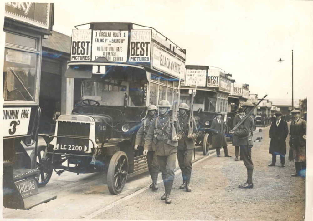 Armed soldiers walking beside a line of black buses.